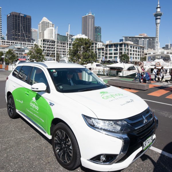 Cityhop car share on Auckland City Centres viaduct with view of skytower, tower blocks, water, boats, pedestrians, and restaurants